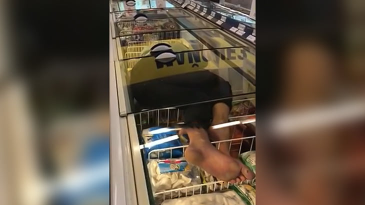 スーパーの冷蔵ショーケースの中に入って寝る男の映像。