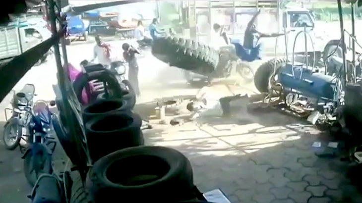 トラックのタイヤが爆発して2人の男性が宙を舞う映像。