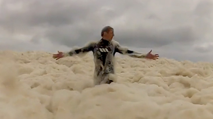 泡だらけの海ではしゃぐサーファーたちの映像。