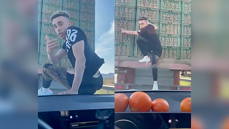 前を走るトラックに乗り移って遊ぶ男の映像。